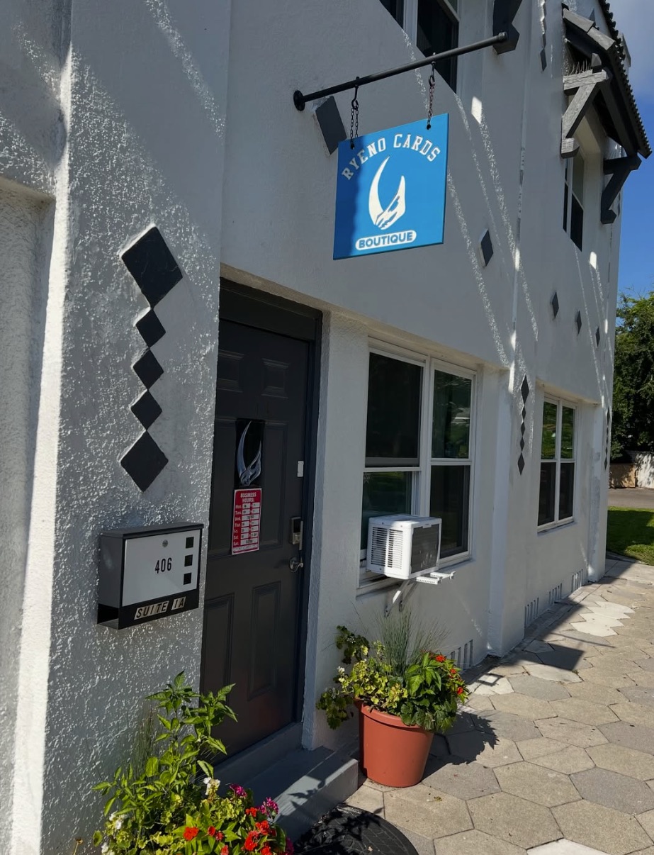 The Ryeno Cards storefront: a white stucco building, door 406, and a blue hanging sign